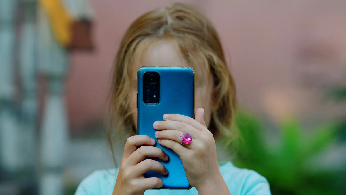 criança com celular na frente do rosto