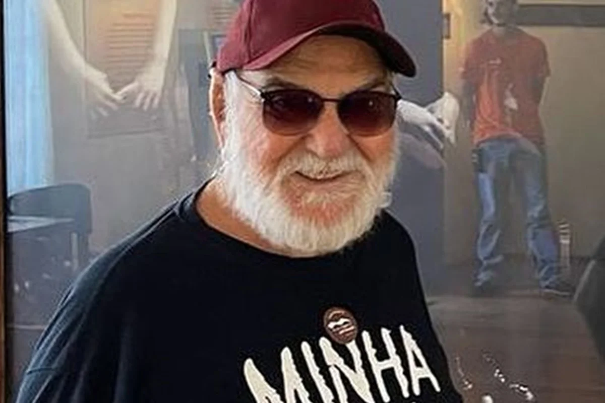 Lima Duarte posa, sorridente, de blusa preta, óculos escuros e boné - Metrópoles