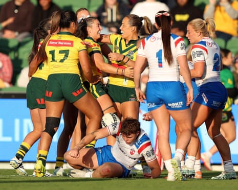 Isabelle Kelly and her Australia teammates celebrate a try as an England player sits on the ground