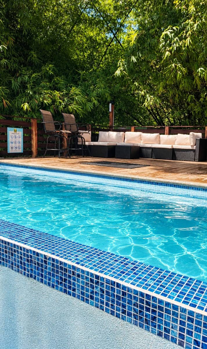 The blue infinity-edge pool, surrounded by lush greenery.