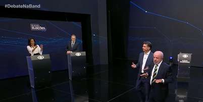 Um dos momentos tensos do debate na Band: os mediadores Adriana Ara&uacute;jo e Eduardo Oinegue precisaram erguer a voz para Fl&aacute;vio Bolsonaro (PL), Lula (PT) e a plateia no est&uacute;dio Foto: Reprodu&ccedil;&atilde;o