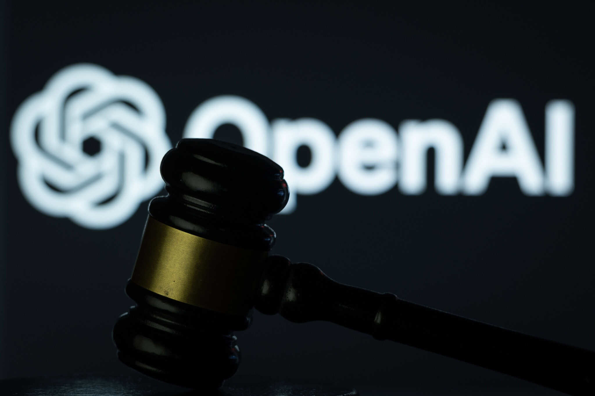 Ao fundo, logo da OpenAI; à frente, martelo de juiz